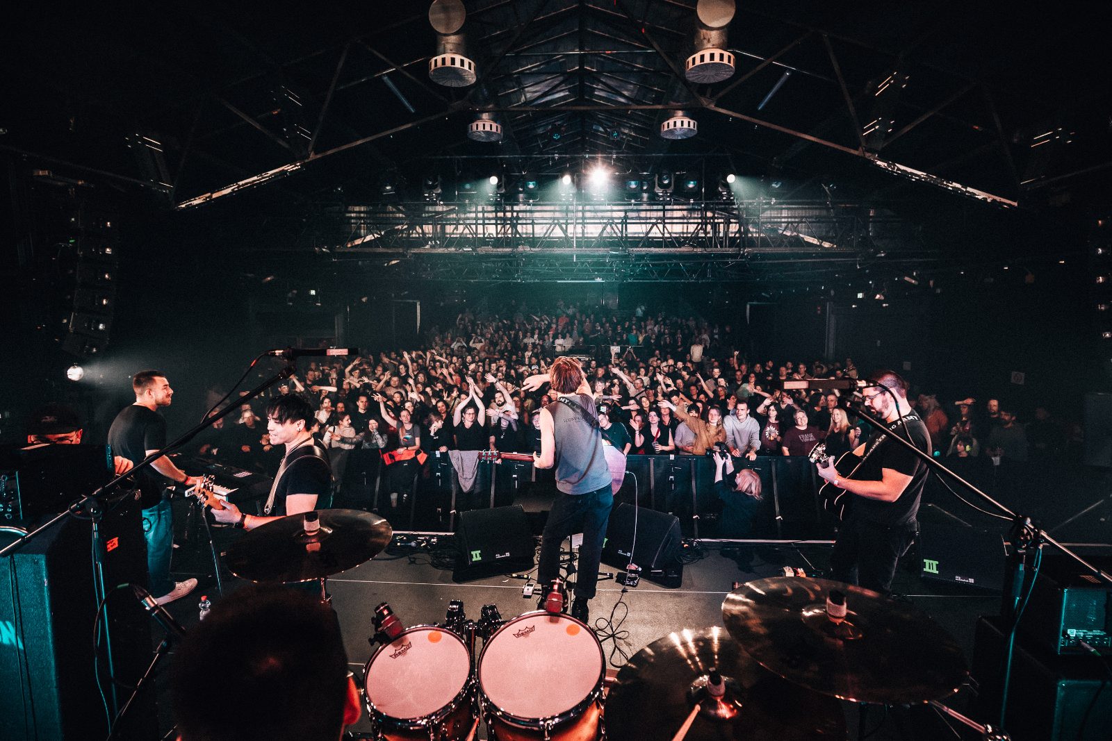 Blick von hinter dem Drumset auf Band und Publikum